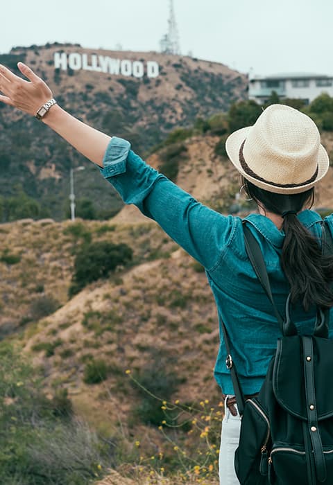 a tourist posed in front of the Hollywood sign